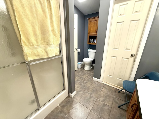 bathroom featuring tile patterned floors, toilet, and a shower with shower door