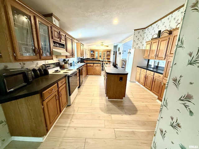 kitchen with light wood-type flooring, a center island, white appliances, ceiling fan, and a textured ceiling