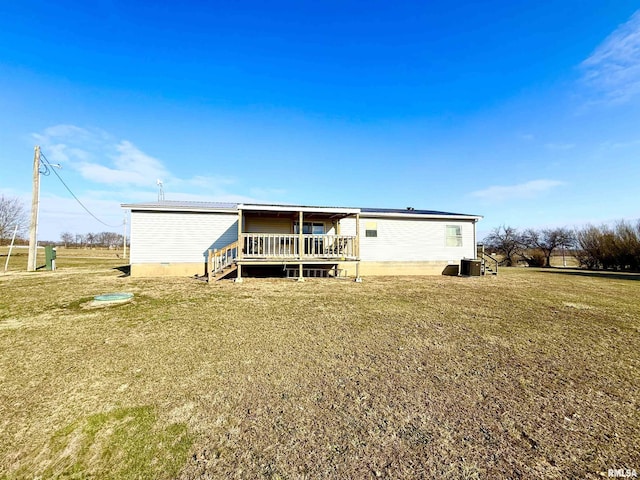 back of property featuring a wooden deck and a lawn