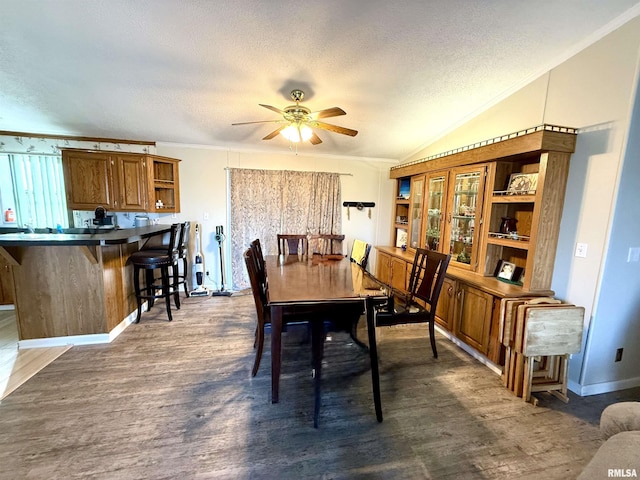 dining area featuring ceiling fan, lofted ceiling, dark hardwood / wood-style flooring, and a textured ceiling