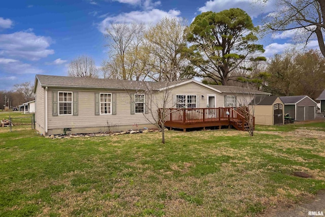 back of property featuring a wooden deck, a yard, and a shed