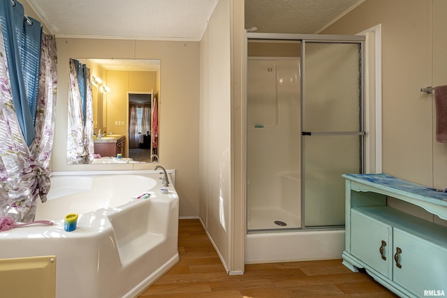 bathroom with crown molding, vanity, wood-type flooring, a textured ceiling, and separate shower and tub