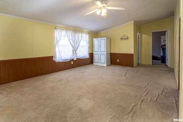 carpeted empty room with crown molding, ceiling fan, and a textured ceiling