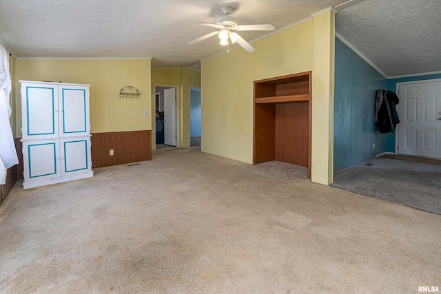 unfurnished bedroom featuring lofted ceiling, carpet floors, ceiling fan, crown molding, and a textured ceiling