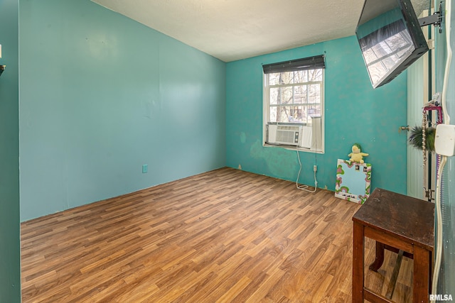 spare room featuring cooling unit, hardwood / wood-style floors, and a textured ceiling