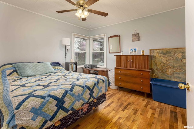 bedroom with ceiling fan, ornamental molding, and light wood-type flooring