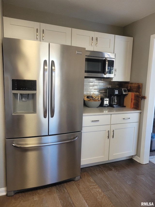 kitchen with stainless steel appliances, dark hardwood / wood-style floors, white cabinets, and decorative backsplash