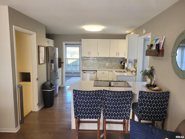 kitchen with sink, appliances with stainless steel finishes, backsplash, white cabinets, and kitchen peninsula