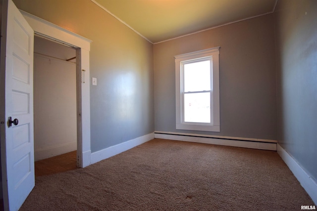 empty room featuring ornamental molding, carpet, and baseboard heating