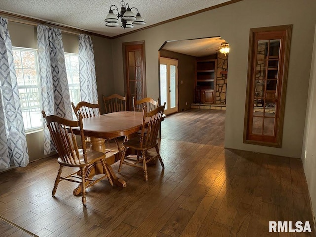 dining area featuring dark wood-type flooring, crown molding, a chandelier, and a textured ceiling