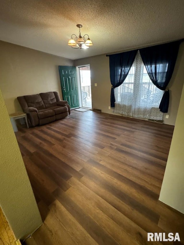 living room featuring dark hardwood / wood-style flooring, a chandelier, and a textured ceiling