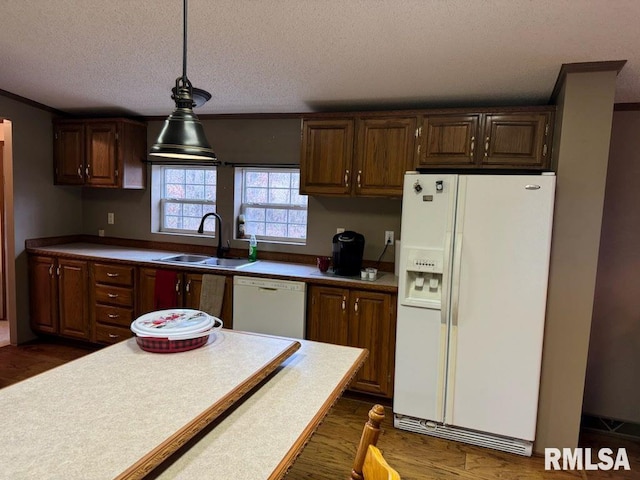 kitchen with pendant lighting, sink, white appliances, dark wood-type flooring, and a textured ceiling