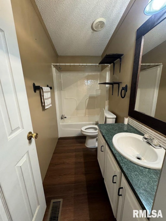 full bathroom with hardwood / wood-style floors, vanity, toilet, a textured ceiling, and washtub / shower combination