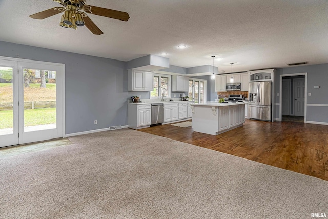 kitchen featuring appliances with stainless steel finishes, a center island, hanging light fixtures, and a textured ceiling