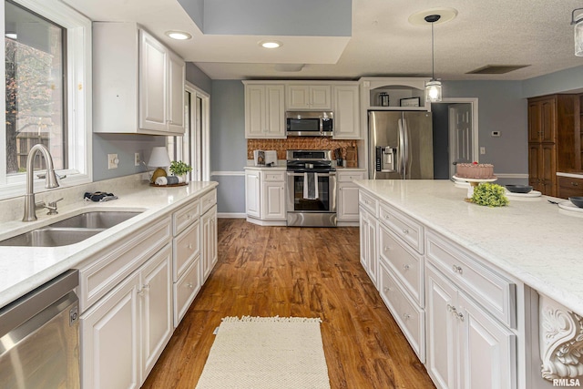 kitchen featuring pendant lighting, sink, dark wood-type flooring, appliances with stainless steel finishes, and light stone counters