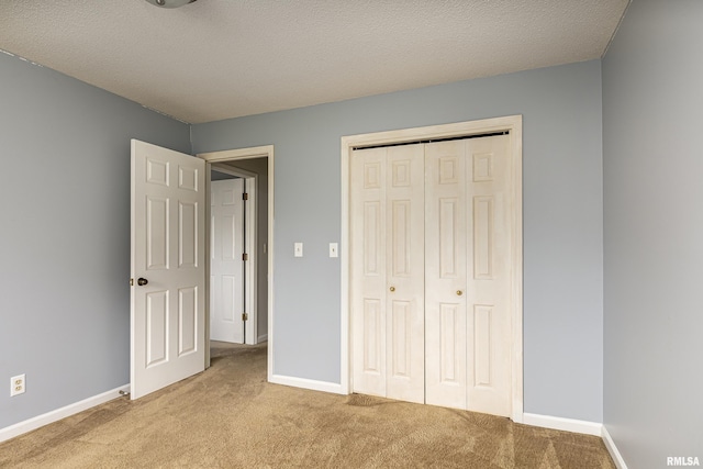 unfurnished bedroom featuring light colored carpet, a closet, and a textured ceiling