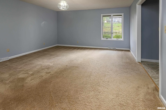 carpeted spare room with a chandelier
