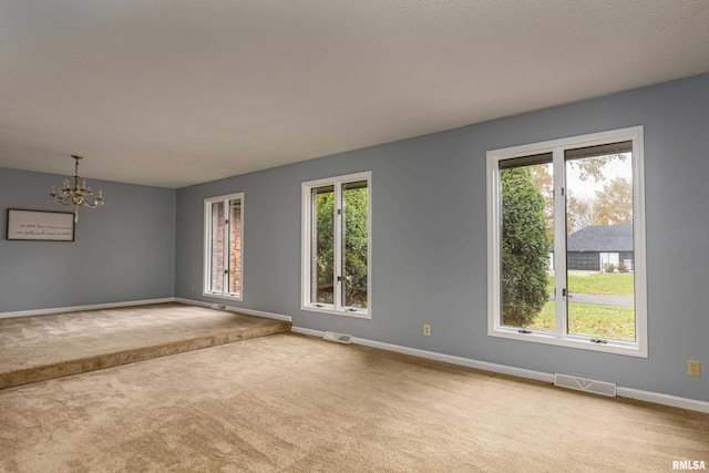 unfurnished room with carpet floors and a notable chandelier