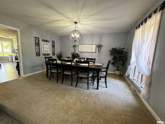 dining area with carpet flooring, a textured ceiling, and a chandelier