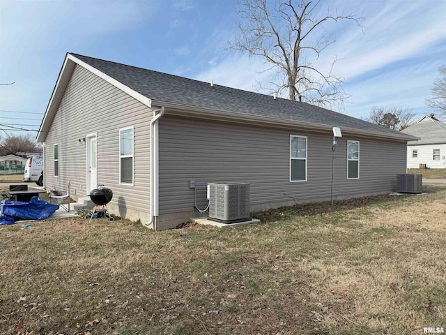 rear view of property with a yard and central air condition unit