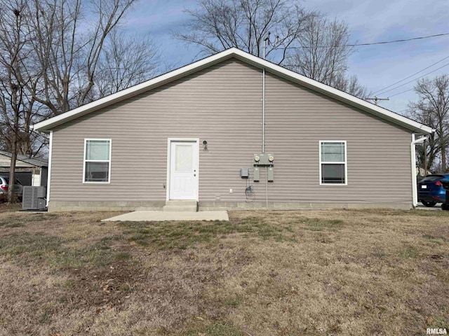 back of house with central AC unit and a yard