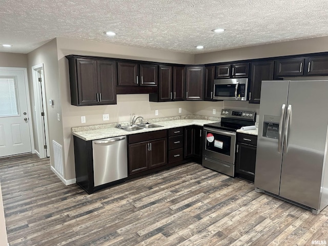 kitchen with wood-type flooring, appliances with stainless steel finishes, sink, and dark brown cabinets