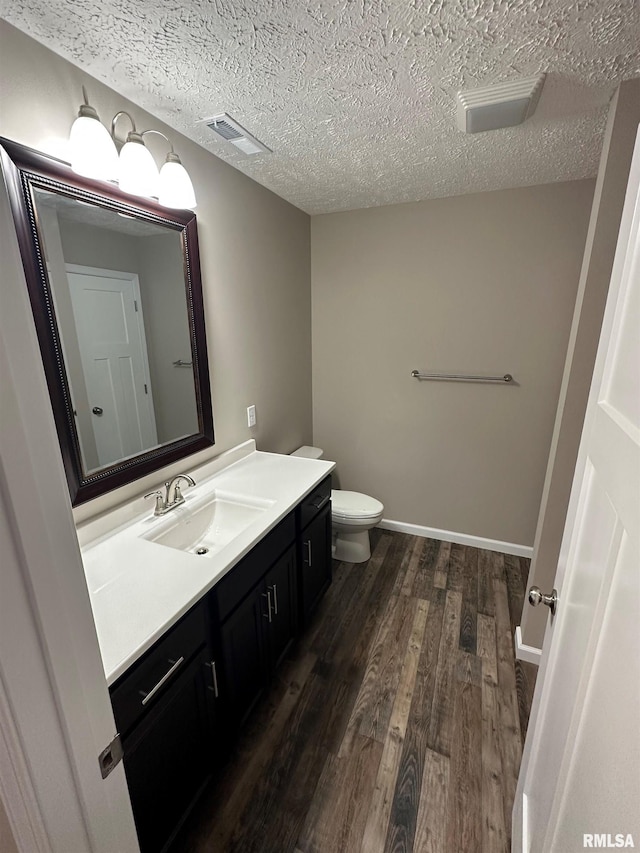 bathroom featuring vanity, hardwood / wood-style floors, toilet, and a textured ceiling