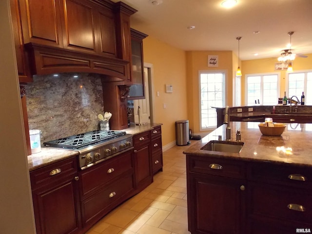 kitchen featuring sink, backsplash, light stone countertops, and stainless steel gas stovetop