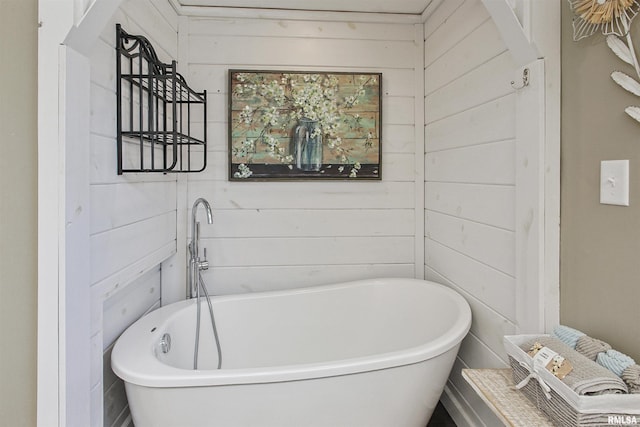 bathroom featuring a bathtub and wooden walls