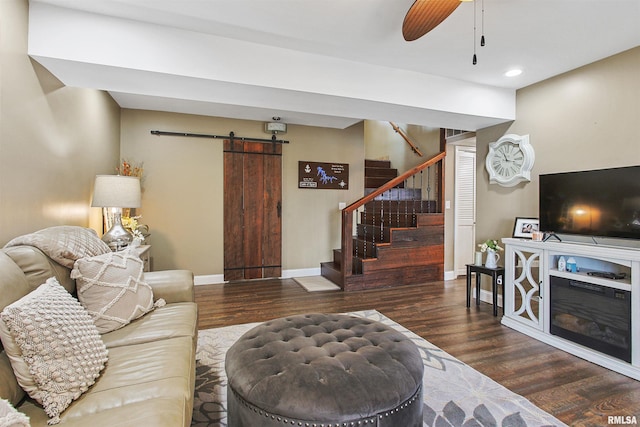 living room with a barn door, dark hardwood / wood-style floors, and ceiling fan