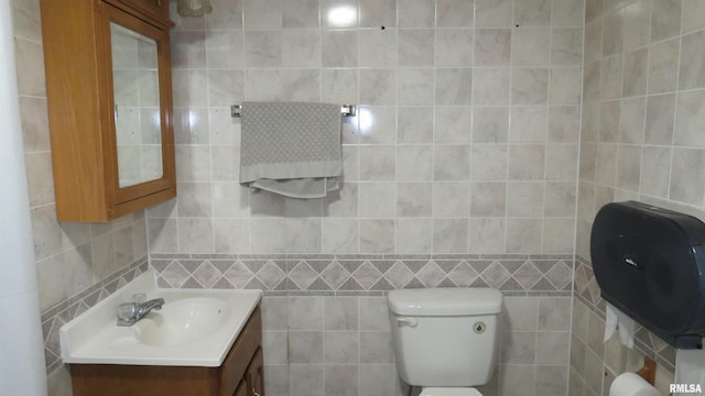 bathroom with vanity, tile walls, and toilet