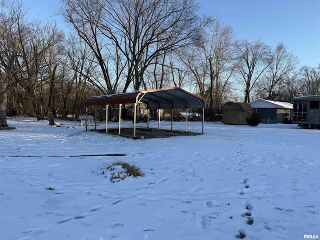 yard covered in snow with a shed and a carport