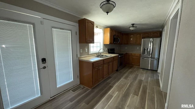 kitchen with crown molding, appliances with stainless steel finishes, sink, and dark hardwood / wood-style flooring