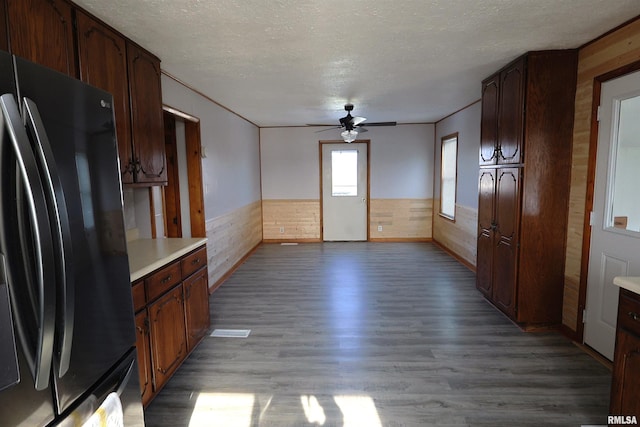 kitchen with hardwood / wood-style flooring, ceiling fan, fridge, a textured ceiling, and wood walls