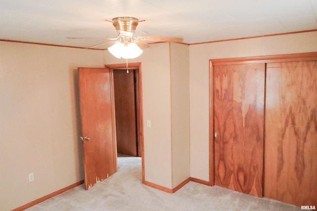 unfurnished bedroom featuring ornamental molding, light carpet, ceiling fan, and a closet