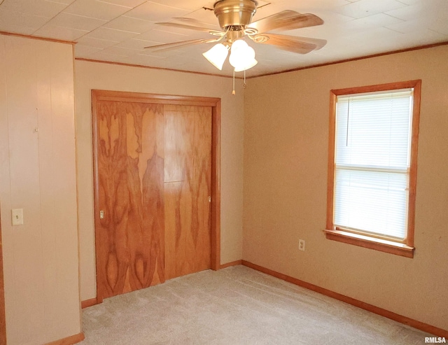 unfurnished bedroom with multiple windows, ornamental molding, light colored carpet, and ceiling fan