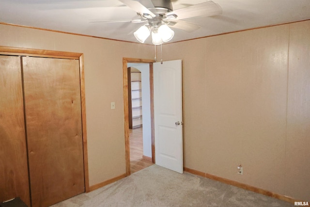 unfurnished bedroom featuring ornamental molding, light carpet, ceiling fan, and a closet