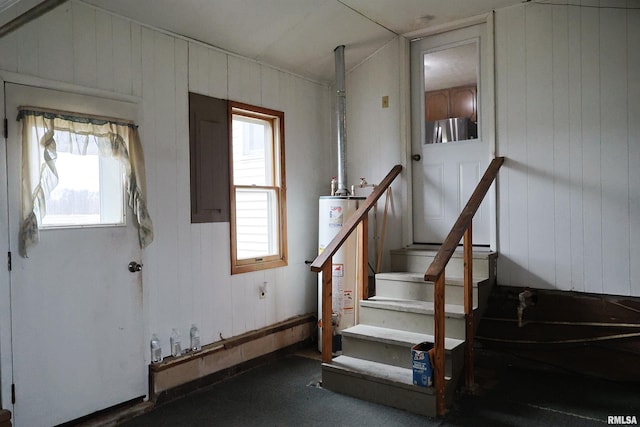 staircase featuring wood walls and gas water heater