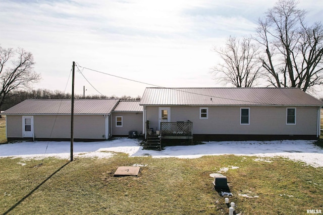 snow covered house featuring central AC and a lawn