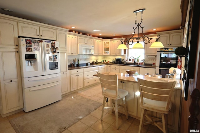 kitchen with light tile patterned floors, white appliances, a kitchen breakfast bar, tasteful backsplash, and decorative light fixtures