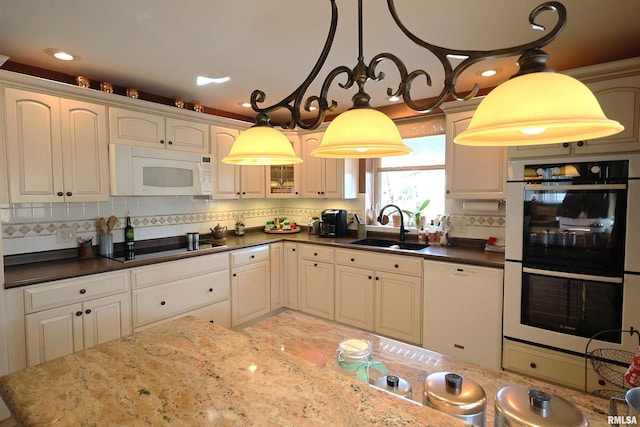 kitchen featuring tasteful backsplash, sink, pendant lighting, and white appliances