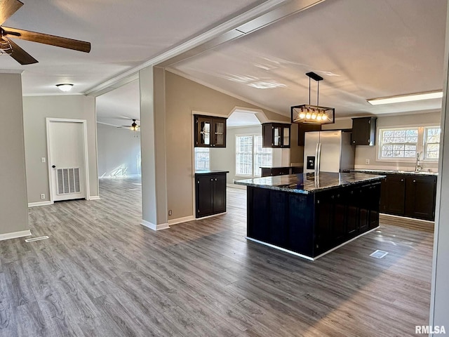 kitchen with hardwood / wood-style floors, decorative light fixtures, dark stone countertops, a center island, and stainless steel refrigerator with ice dispenser