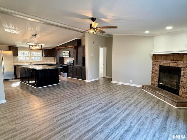 kitchen with sink, a center island, appliances with stainless steel finishes, pendant lighting, and a fireplace