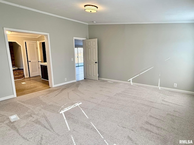 unfurnished bedroom featuring crown molding, ensuite bathroom, and light carpet