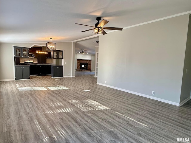 unfurnished living room with a fireplace, crown molding, vaulted ceiling, and dark hardwood / wood-style floors