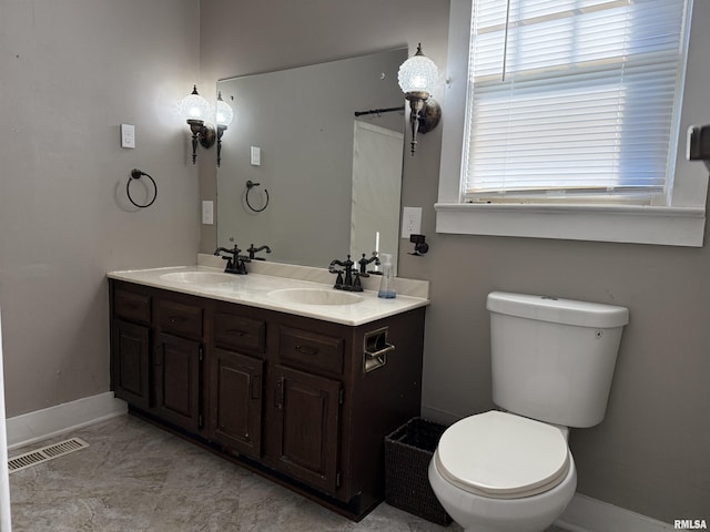 bathroom featuring double vanity, visible vents, toilet, and a sink