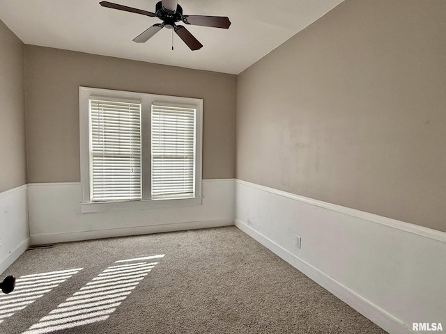 spare room featuring light carpet, ceiling fan, and baseboards