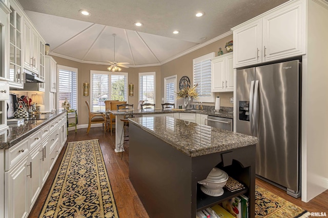 kitchen with a kitchen island, appliances with stainless steel finishes, dark stone countertops, white cabinets, and ceiling fan