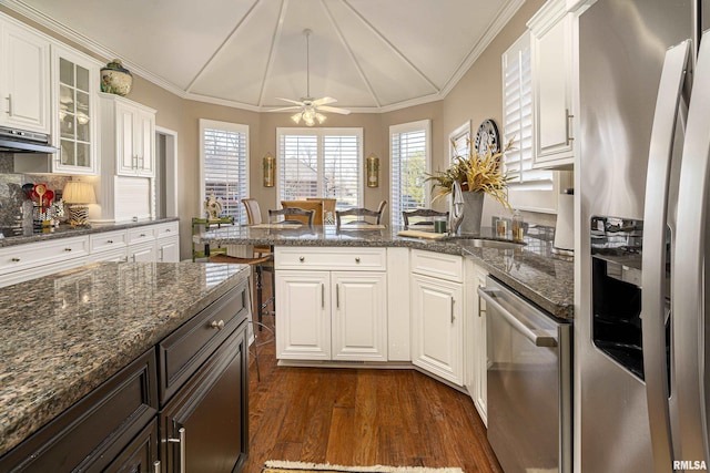 kitchen with appliances with stainless steel finishes, white cabinets, dark hardwood / wood-style flooring, and dark stone counters