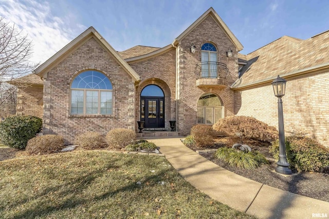 view of front of house featuring a front lawn, french doors, and a balcony